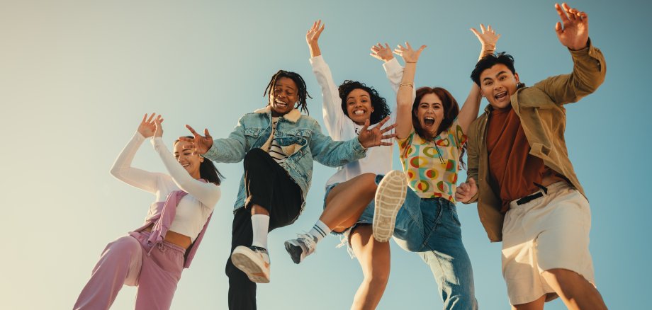 Group of friends jumping and having fun outdoors in the sunshine